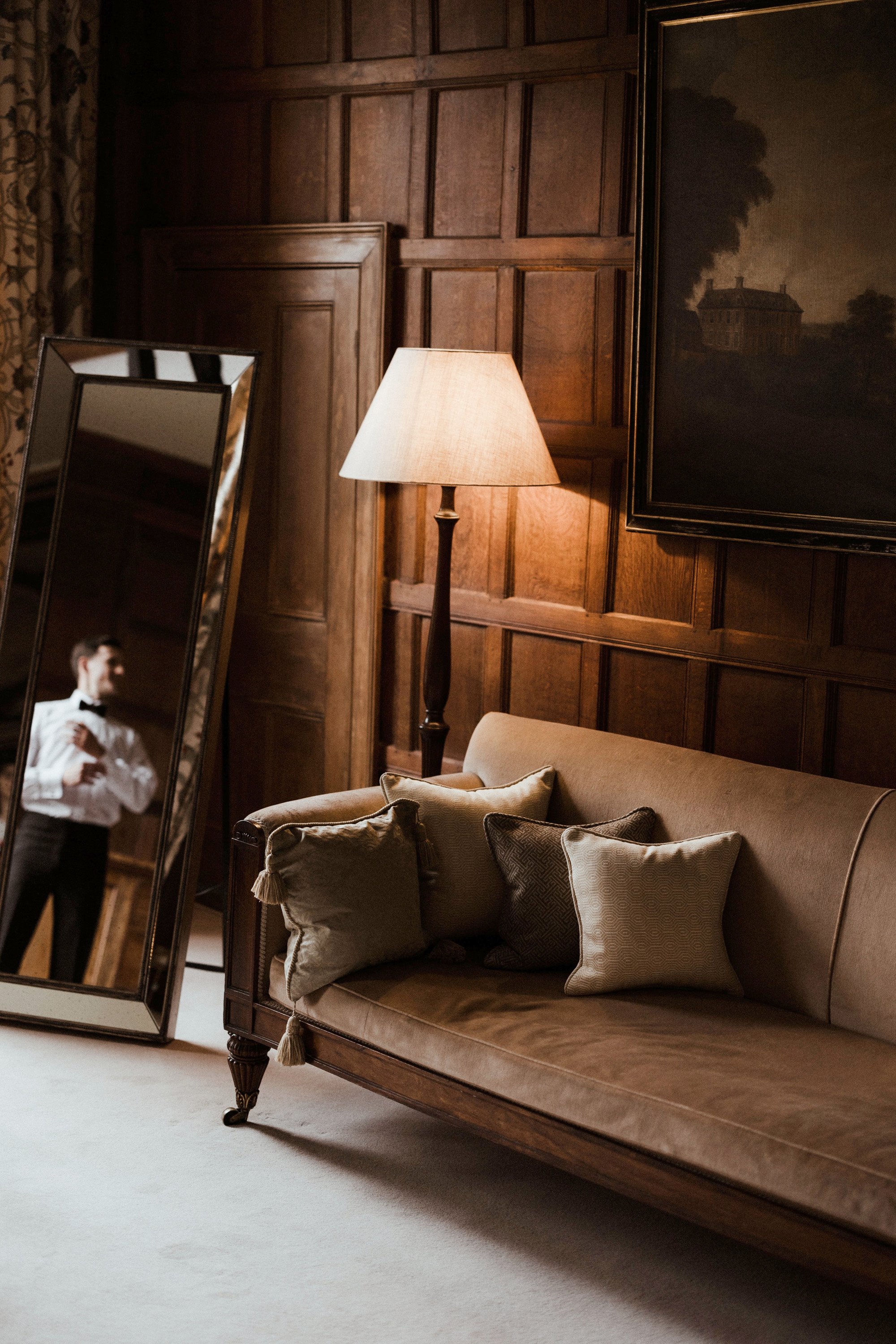 Groom getting ready in traditional english stately home wedding venue bedroom on his fine art editorial wedding day