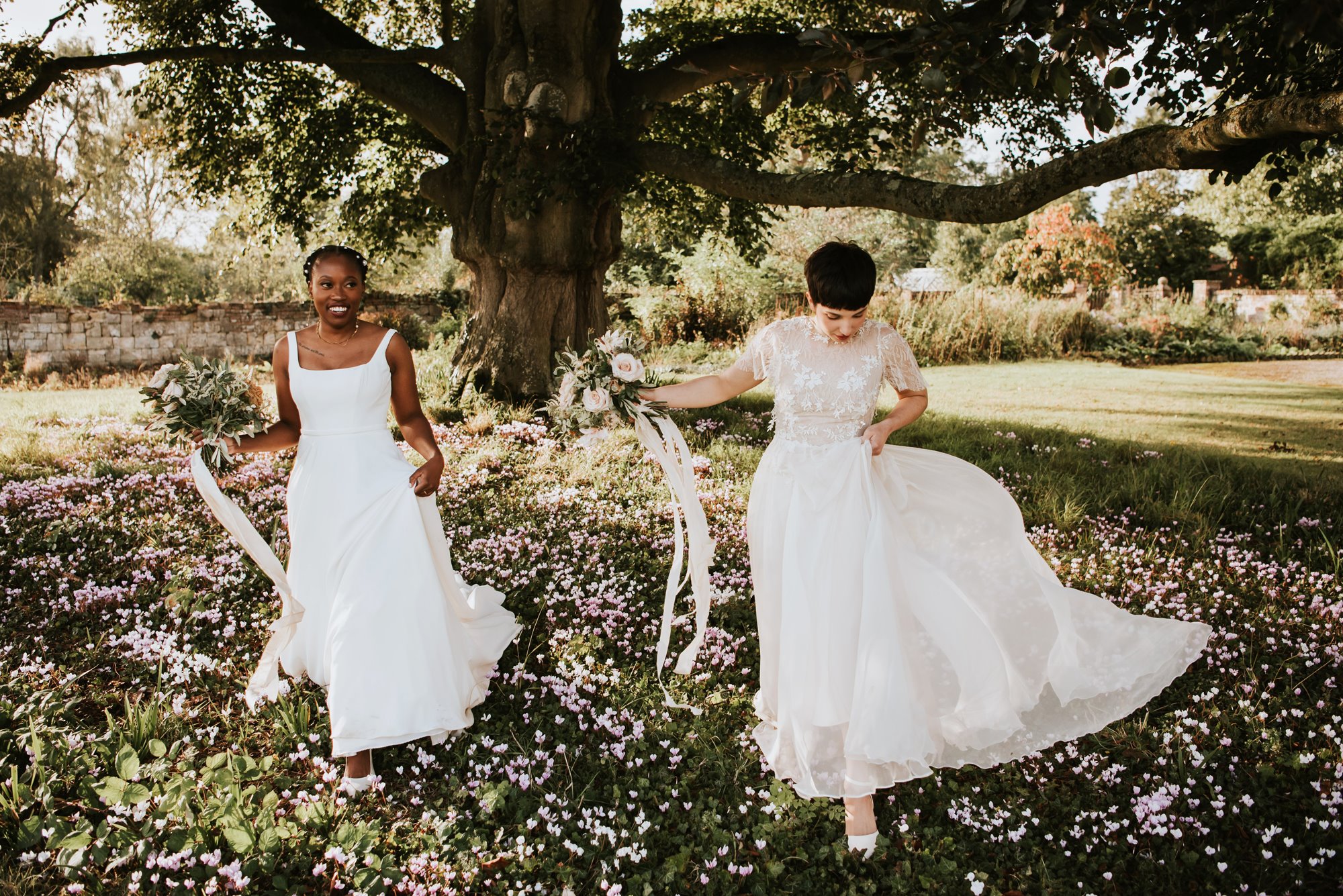 two brides under a magnificent tree at their summer wedding