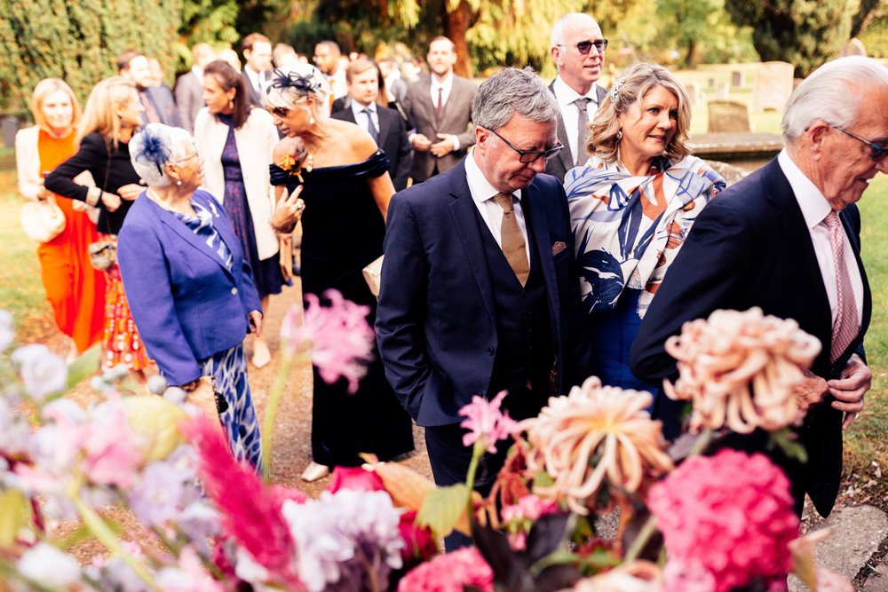 guests arrive for church wedding ceremony with colourful flowers 