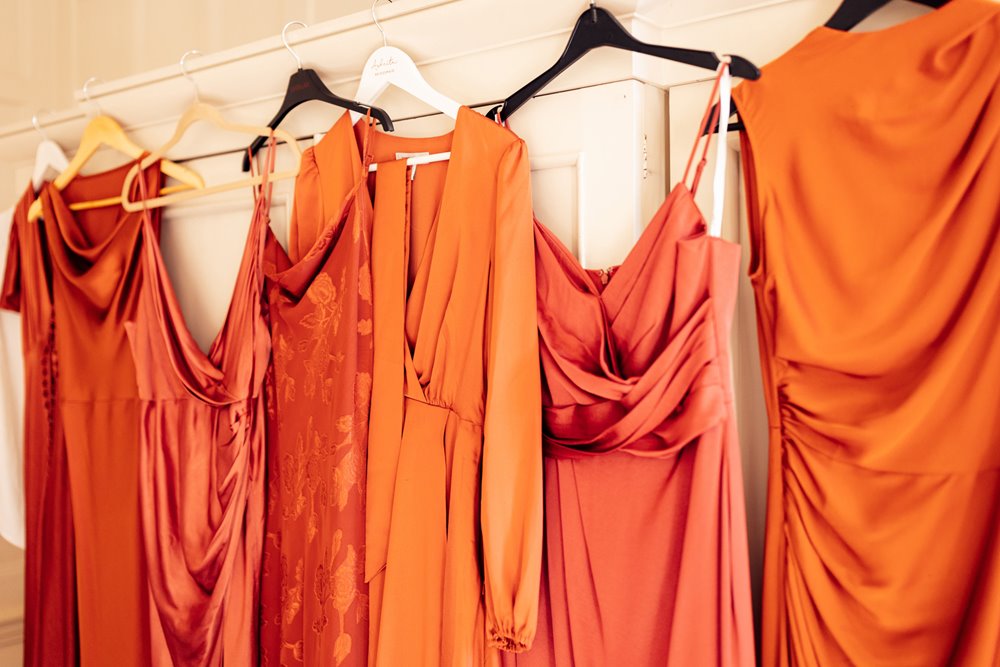 colourful orange bridemaids dresses hanging ready on wedding morning