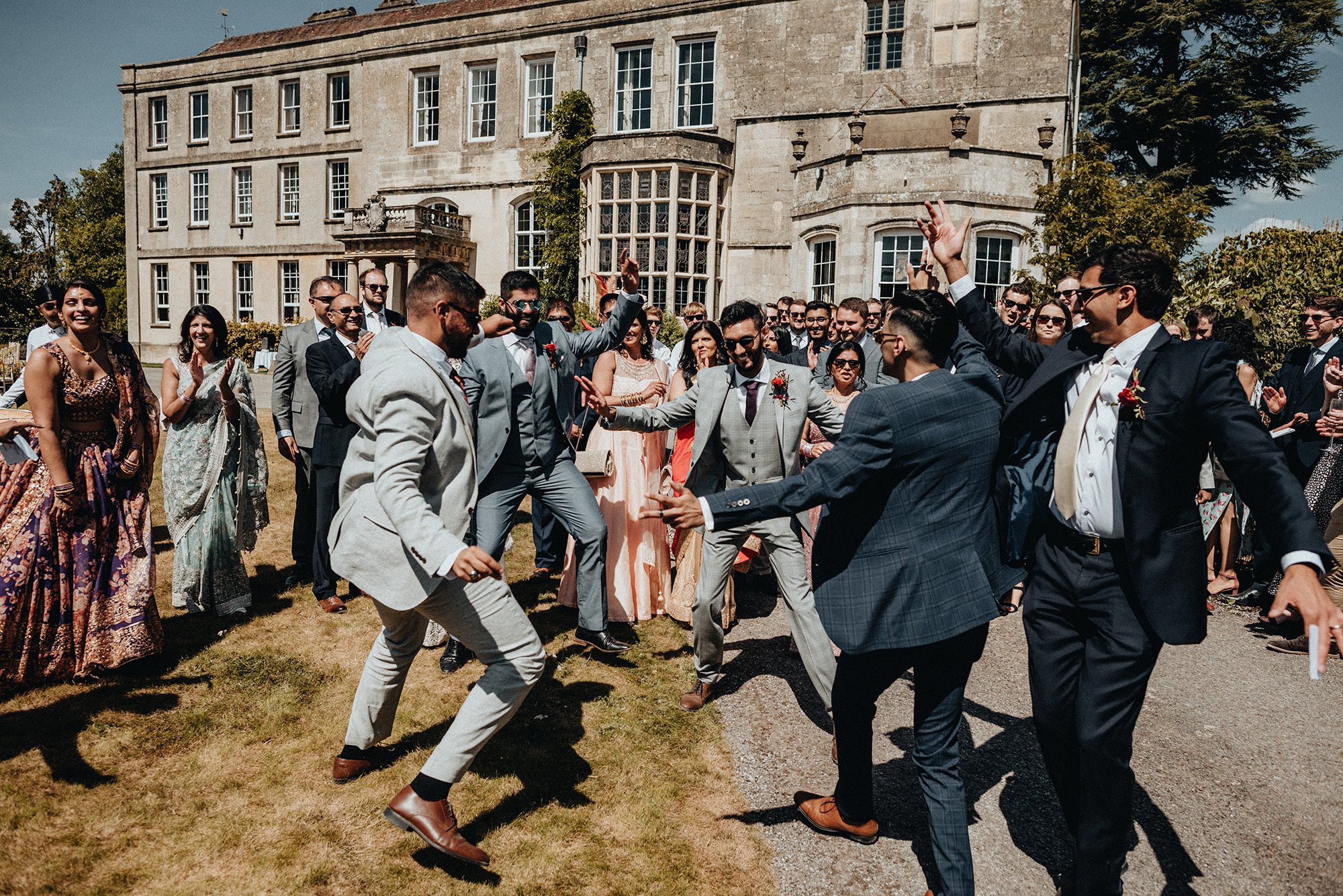 guests dancing in front of stately home for a party wedding with outdoor ceremony