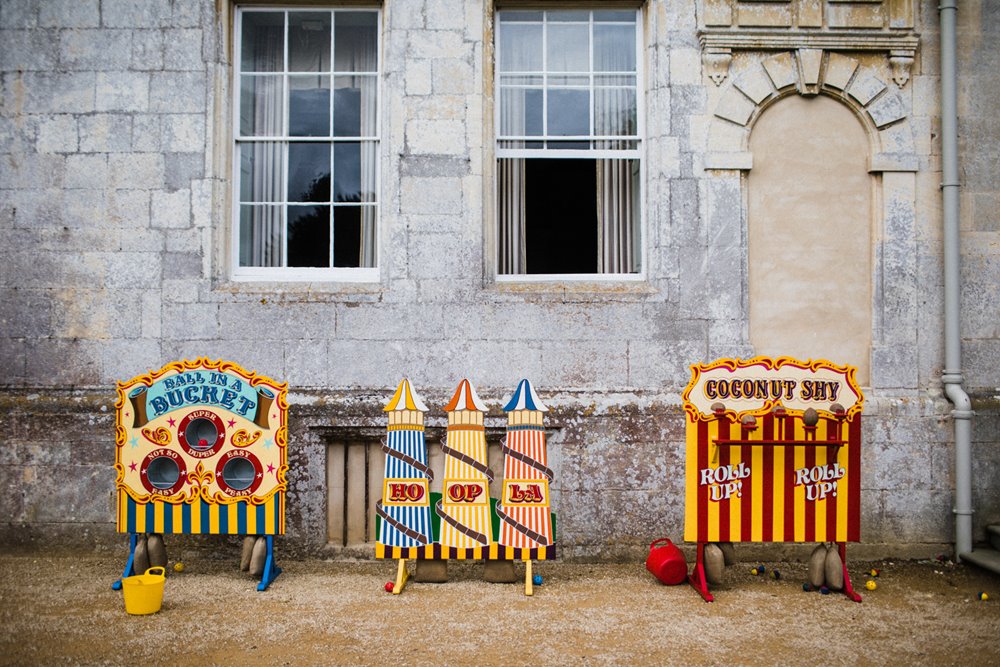 Vintage fairground style games set up against mansion house elmore court for a garden wedding with a festival feel