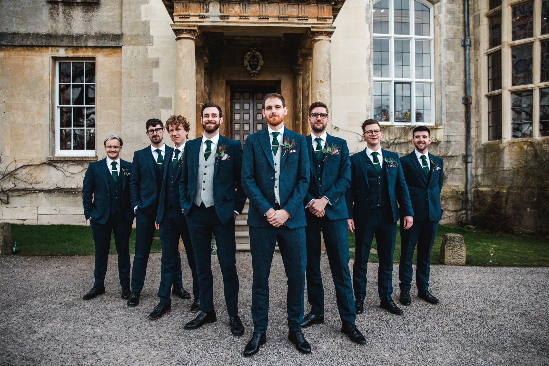 7 smartly dressed Groomsmen stand to attention outside grade 2 listed mansion house weekend wedding venue