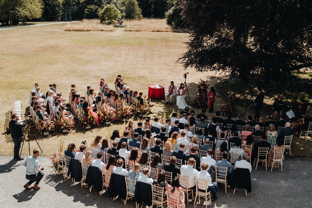 outdoor wedding ceremony next to a magnificent stately home on the lawn in summer
