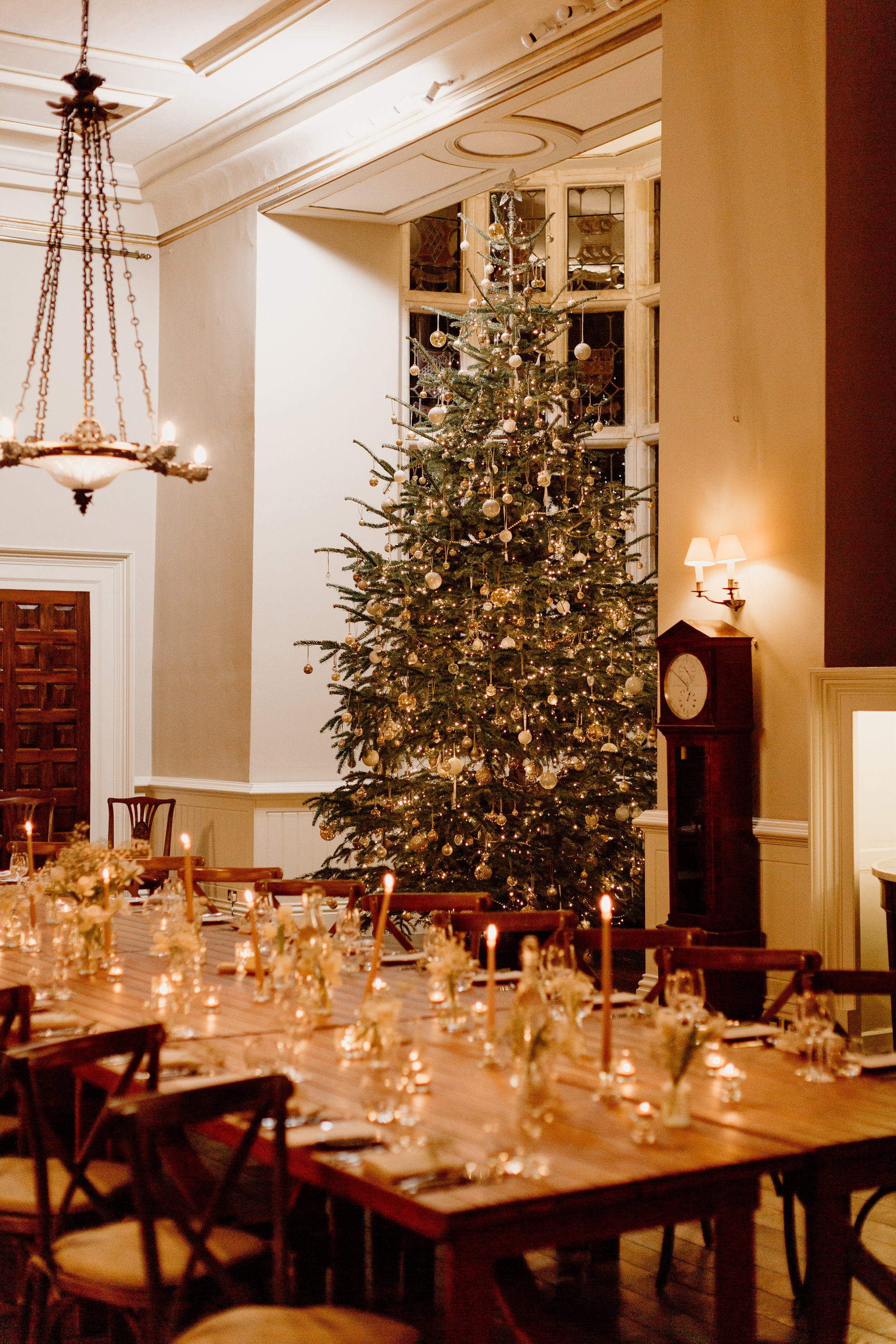 candle lit table setting in the great hall of Elmore Court with an impressively tall Christmas tree