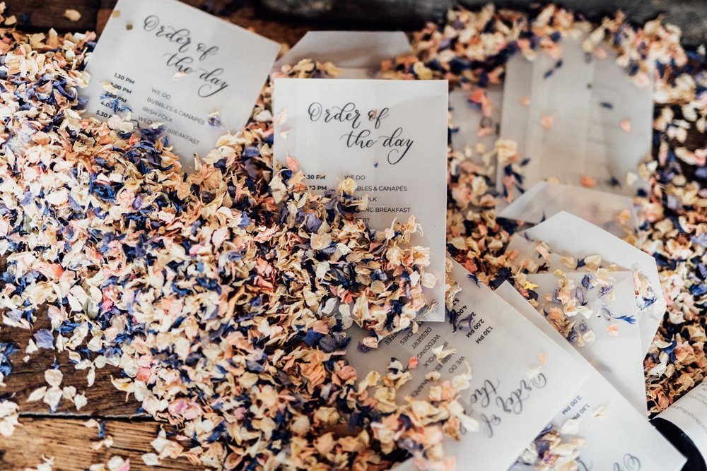 order of services for a wedding, surrounded by stunning pastel flower petal confetti