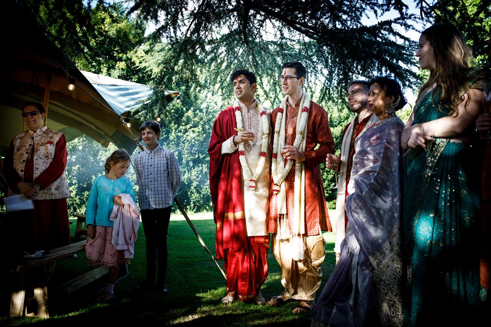Two grooms beautifully dressed in traditional Indian wedding attire at an outdoor ceremony and Hindu blessing at wedding venue elmore court