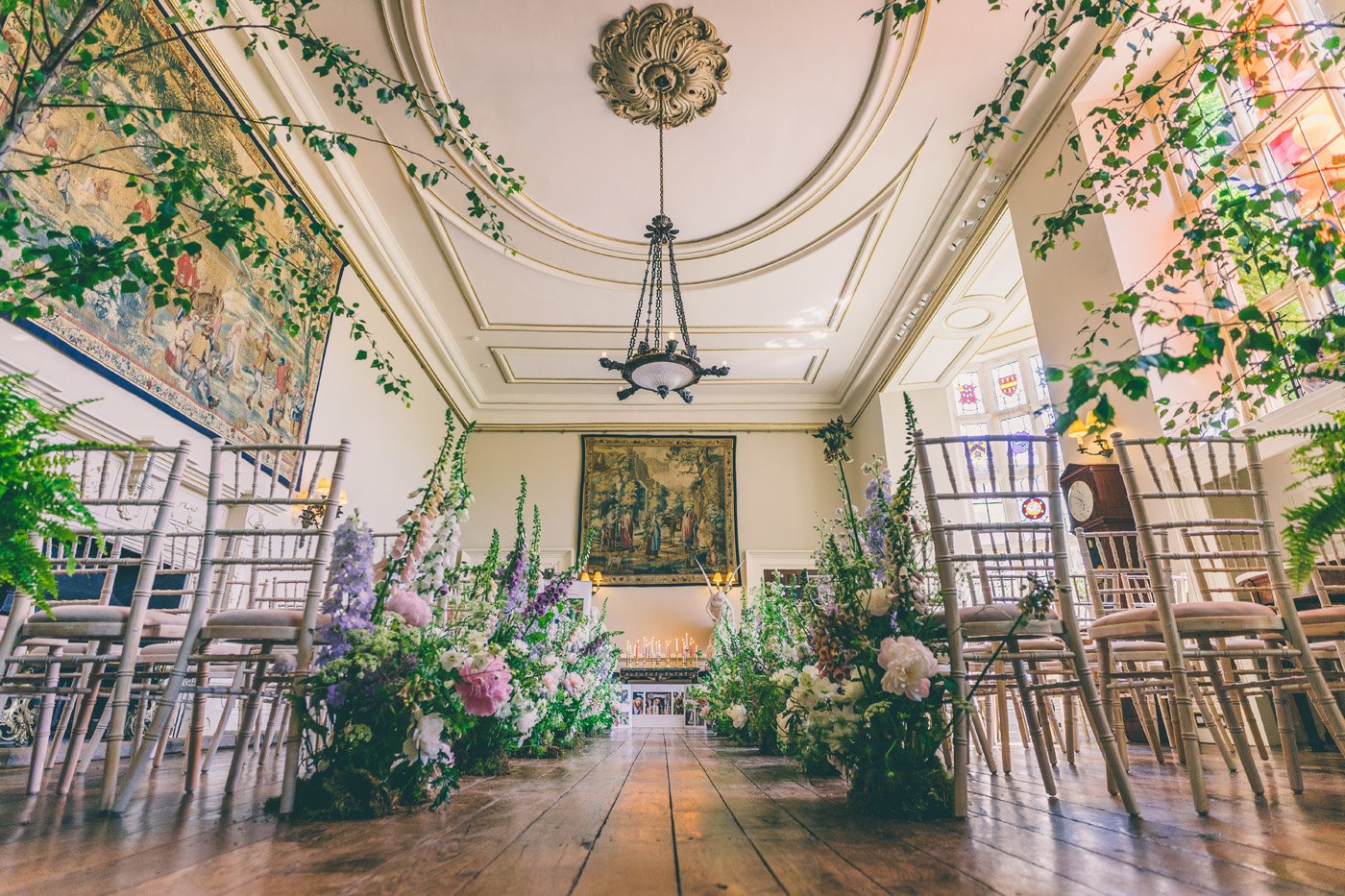 Stunning floral wedding aisle with tall wildflower arrangements and trees flanking the wedding aisle in the ceremony hall at Elmore Court in Gloucestershire