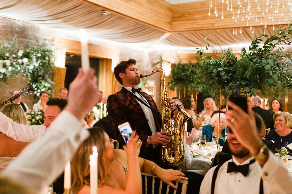 Saxophonist plays to seated wedding guests in magical wedding reception venue the gillyflower at elmore court