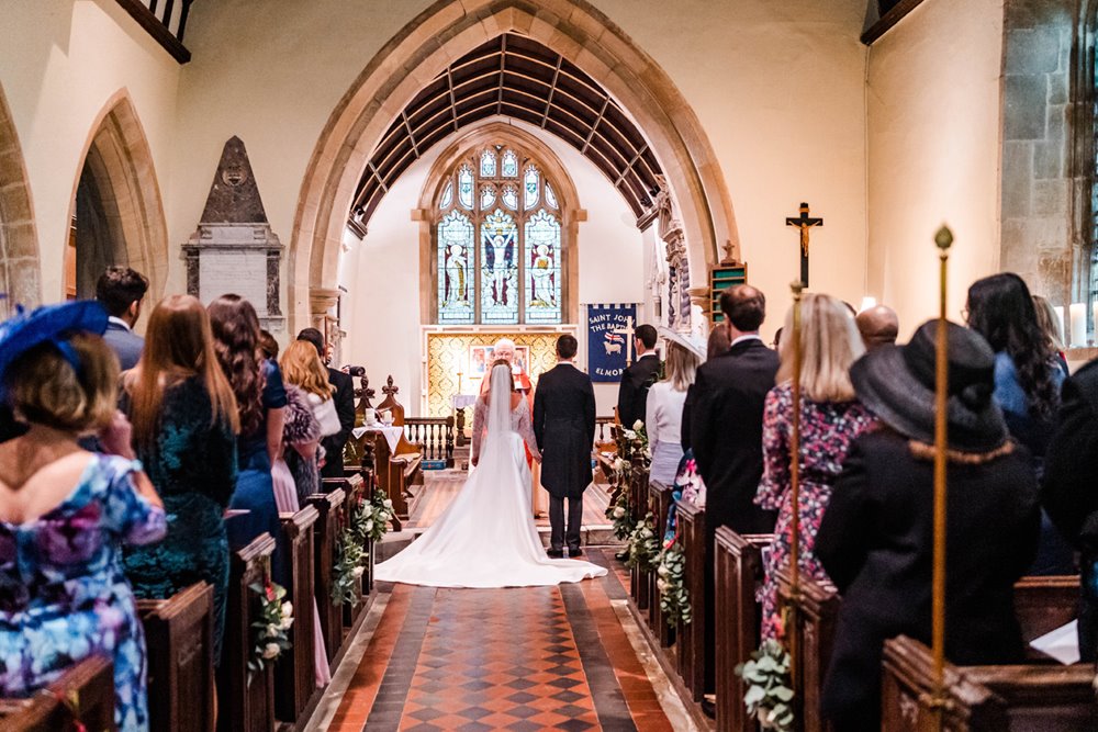 Bride and groom in middle of wedding service at pretty church at Elmore in gloucestershire