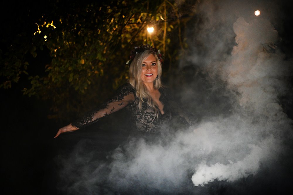 Spooky wedding photos with bride in black lace wedding dress with smoke bomb for halloween 