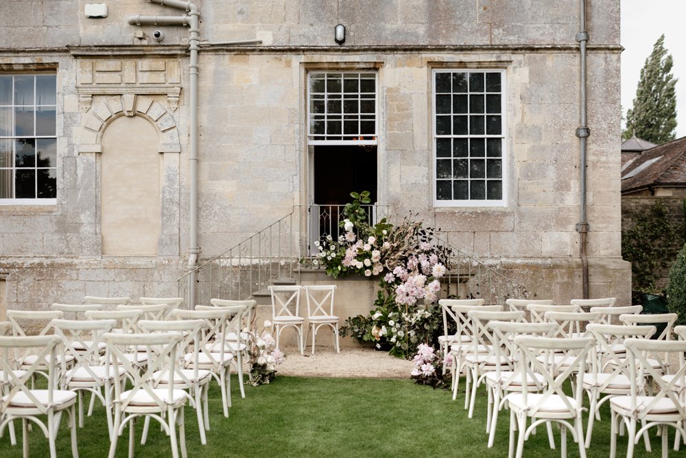 outdoor wedding ceremony next to a magnificent stately home on the lawn in summer