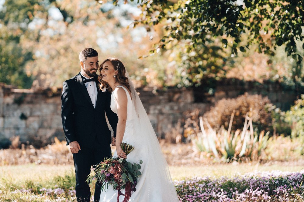 Bride and groom laugh at their october wedding in the walled gardens of wedding venue in the cotswolds