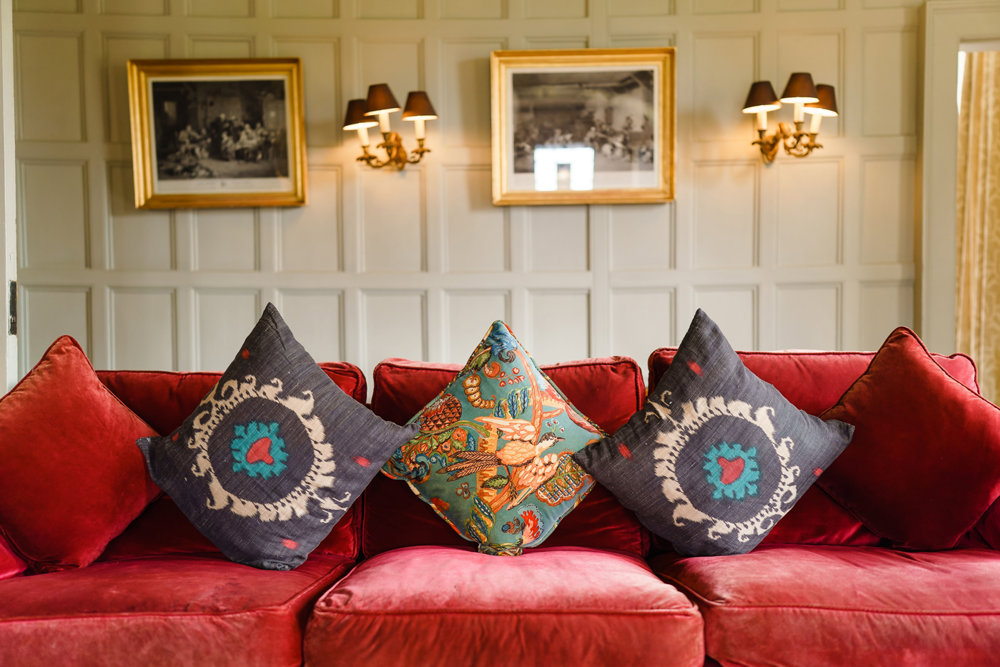red velvet sofa and pale green wood panelling of the drawing room at stately home wedding venue elmore court in the costwolds