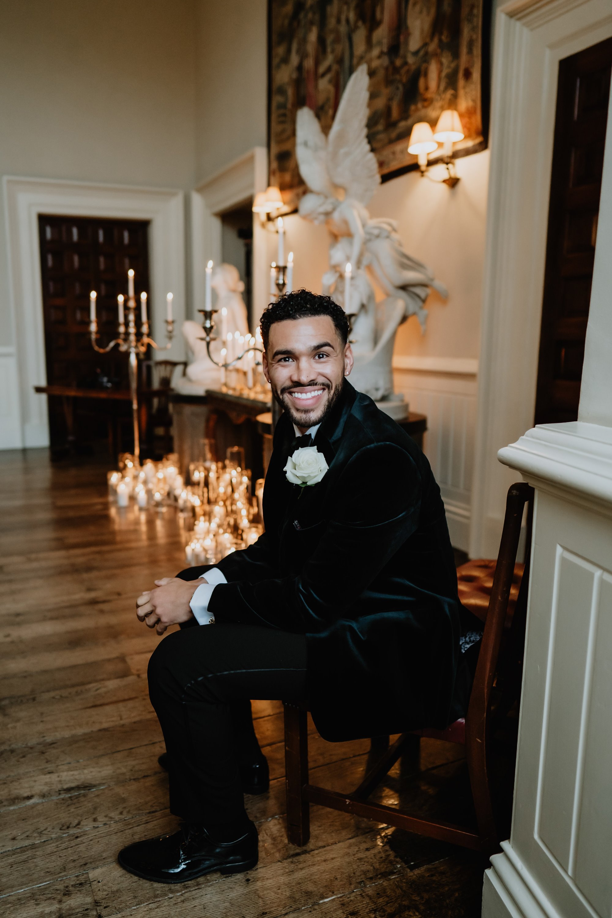 Groom with a huge smile, waiting for his beautiful bride to walk down the aisle in a candle lit great hall of Elmore Court