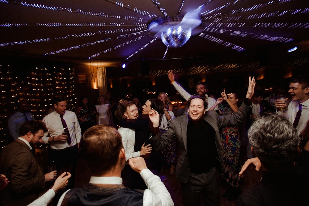 Big party wedding with purple lighting on the dance floor at best festival wedding venue elmore court