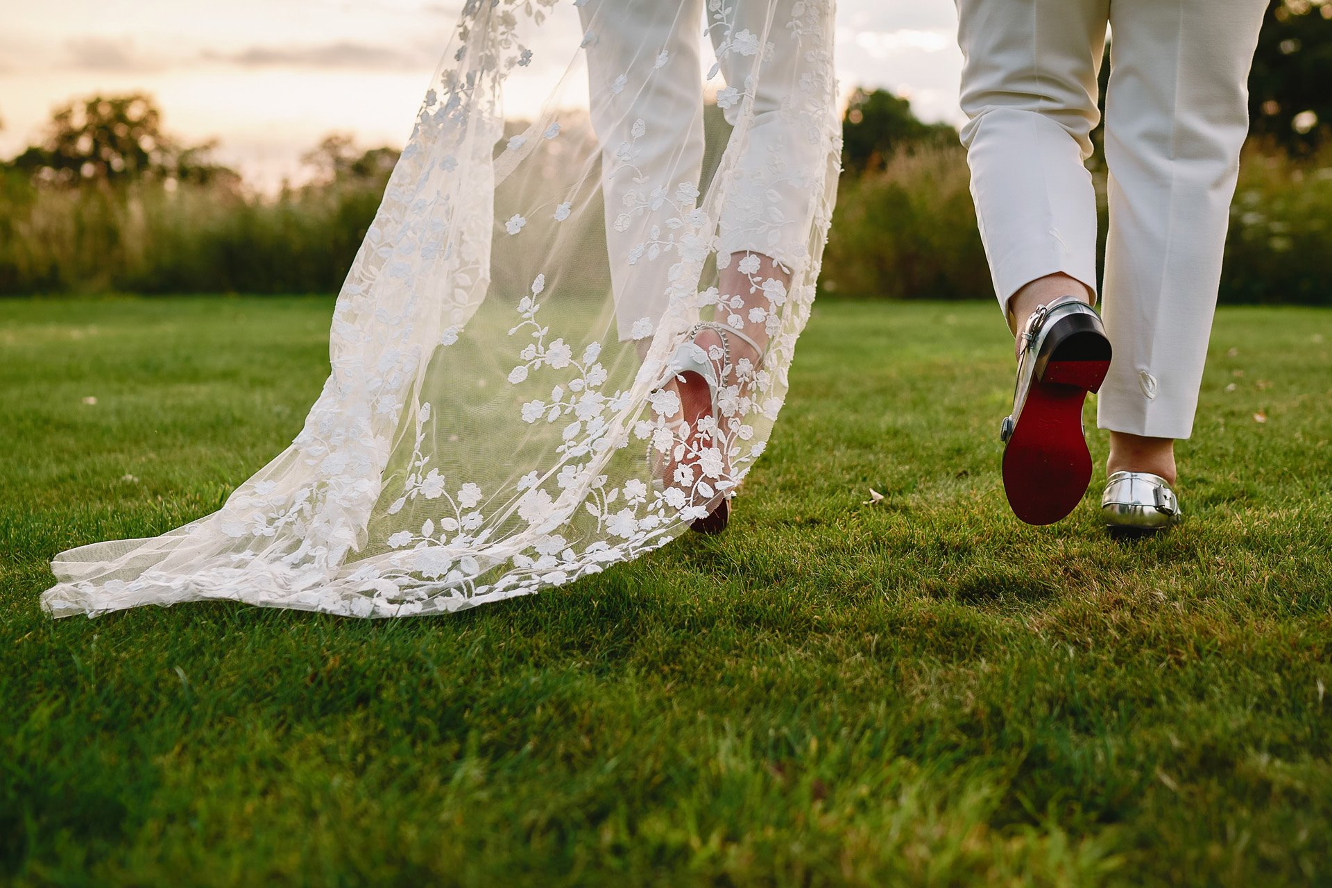 Two brides wearing Louboutin's walking into the sunset on their wedding day at Elmore Court