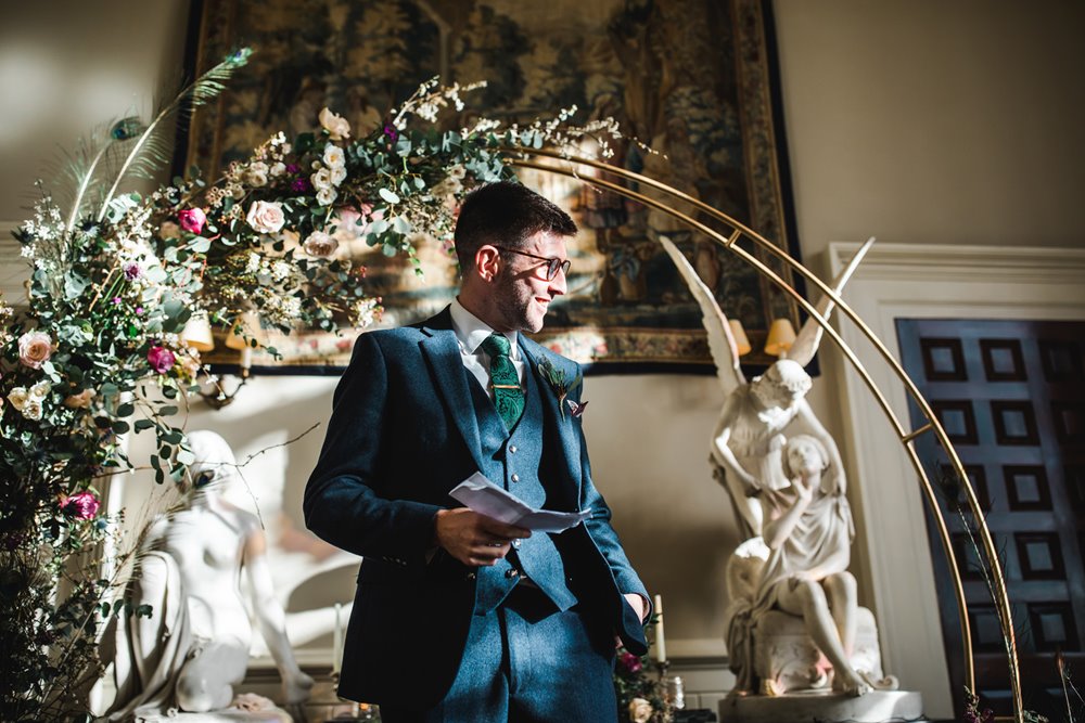 Poetry reading in front of Floral arch backdrop at wedding ceremony on first day of weekend wedding