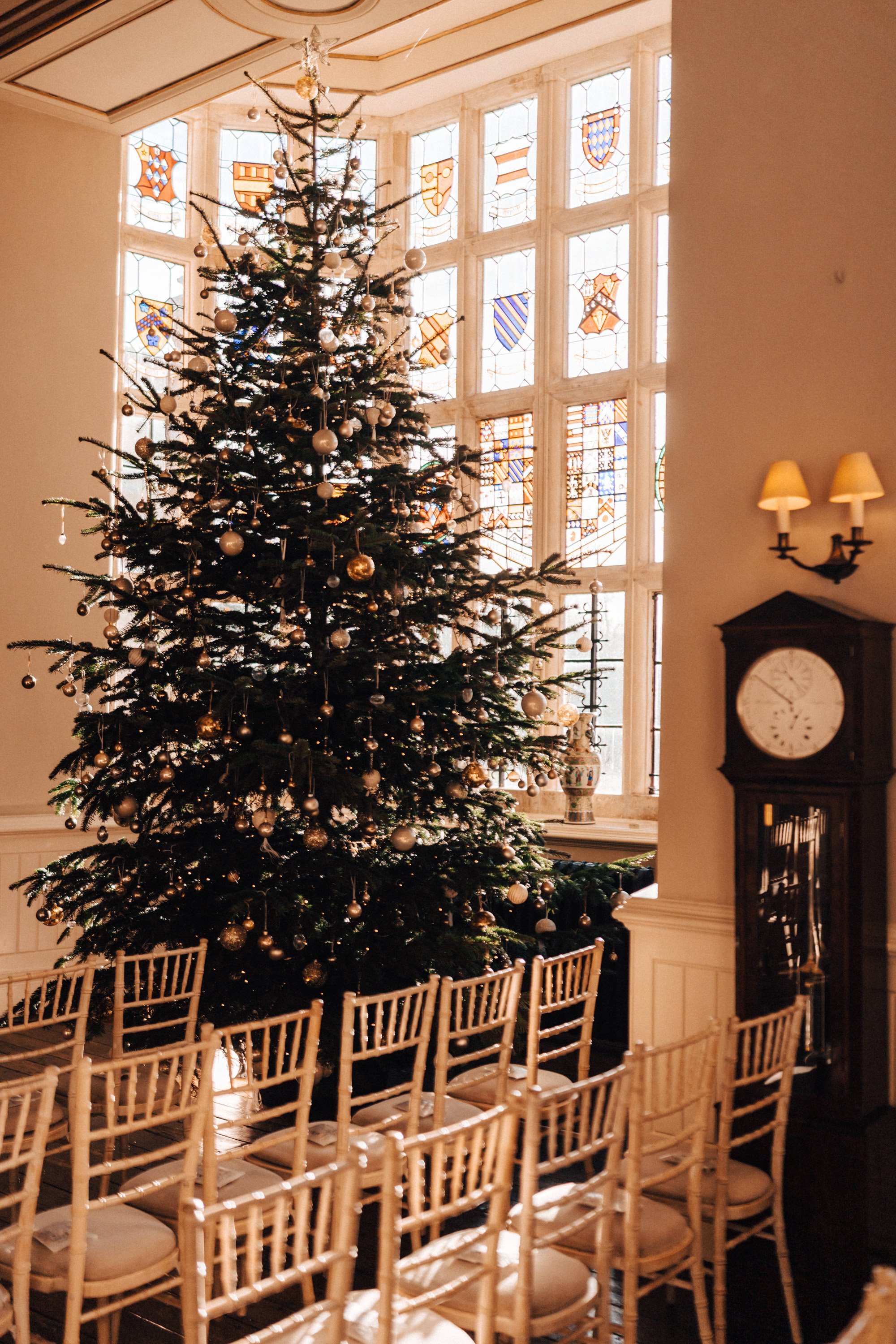 Huge Christmas tree in beautiful mullion window of winter wedding venue stately home in the UK