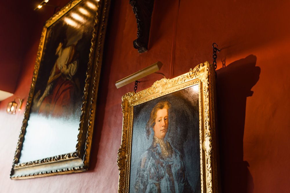 Country house rescue turned successful wedding venue red hallway with paintings of ancestors at elmore court
