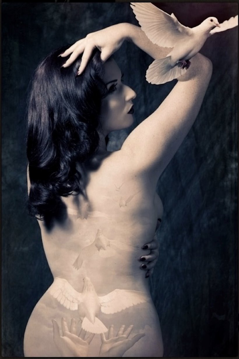 Burlesque performer stands with back to camera releasing a white dove from her body. Burlesque show near Cheltenham