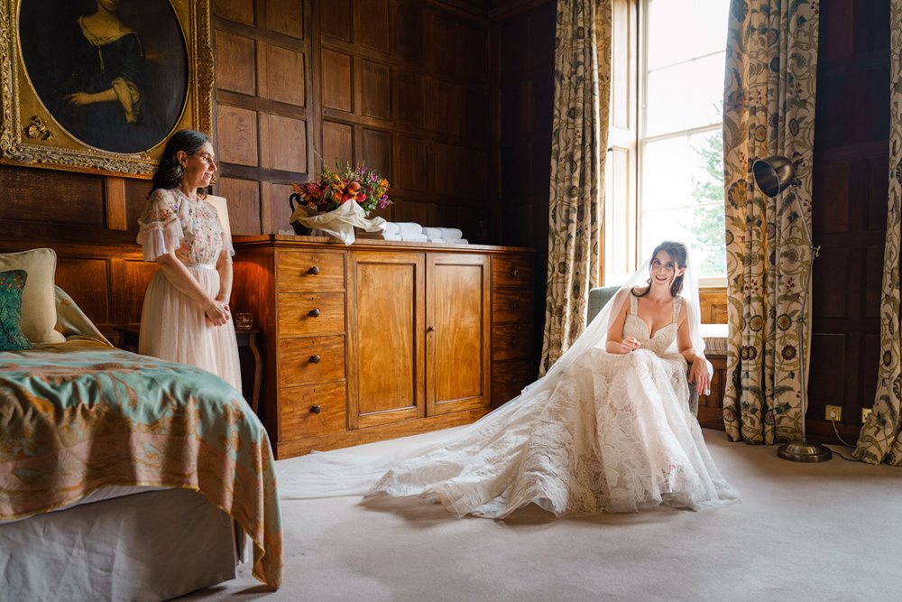 Bride sits in historic wood paneled bedroom in huge wedding dress at elmore court