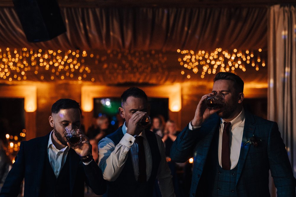 groomsmen drinking together at christmas wedding party