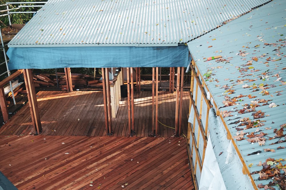 View from the roof of a woodland treehouse, looking down onto an outdoor decked area