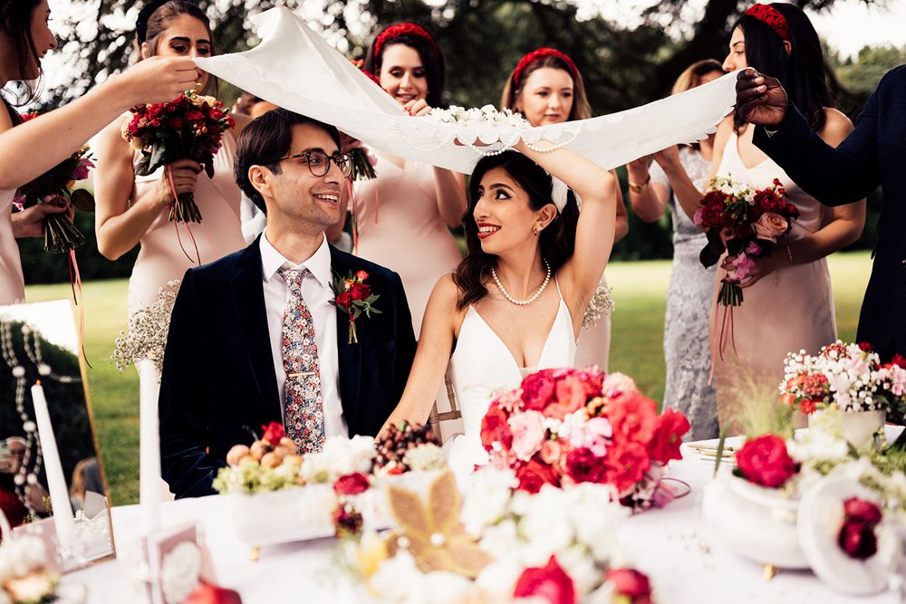 Traditional persian wedding sugar ceremony bride and groom sitting under silk at elmore court