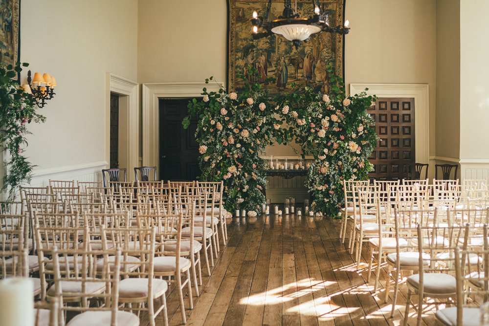 romantoc rose arch at the end of the aisle of wedding ceremony in hall of elmore court