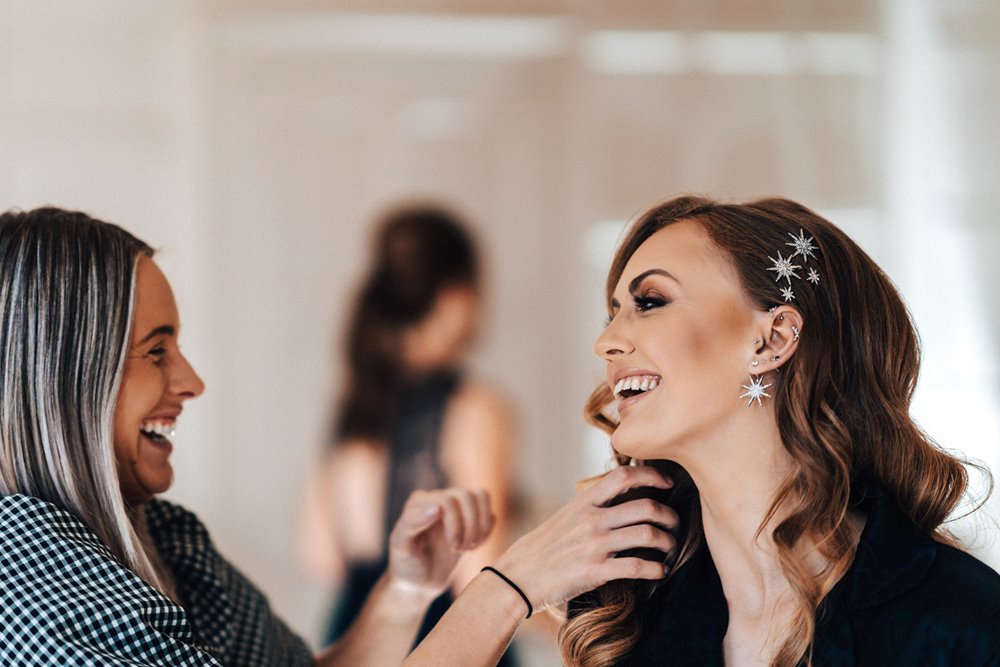beautiful bride laughs showing off her celestial wedding detail earrings and hair for a magical october wedding in the cotswolds