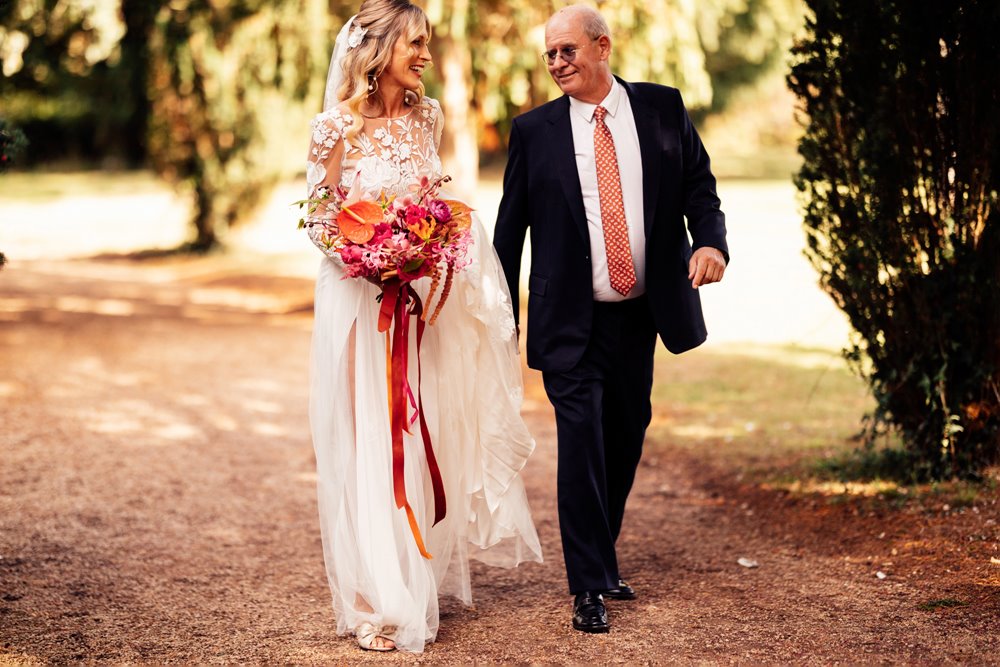 bride and father walking to church in the cotswolds