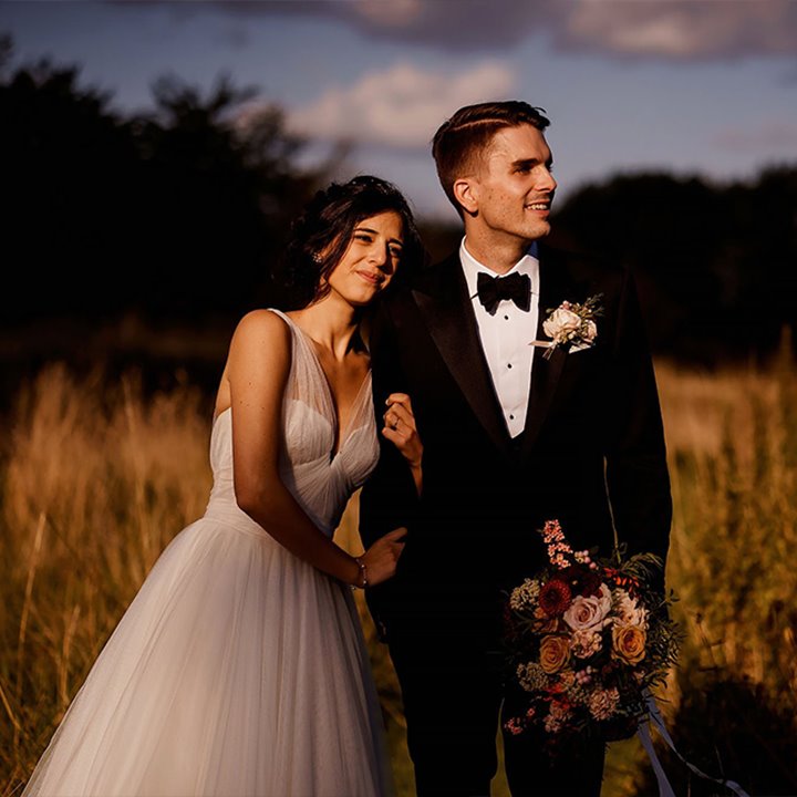 Newly wed couple embracing in a wildflower meadow during a golden hour sun set at Elmore Court