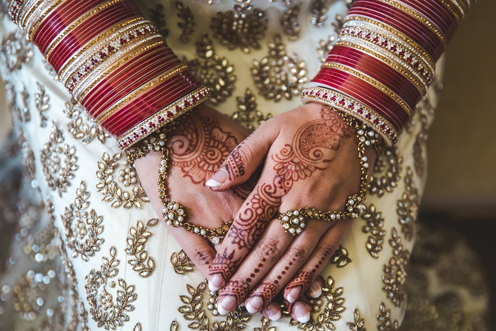 Mehndi on brides hands with red bangles for a beautiful indian wedding in the cotswolds
