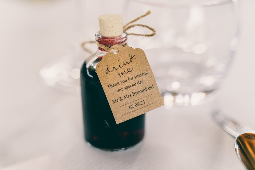 Alice in wonderland tea party inspired wedding with little bottles with tags reading drink me on wedding tables at festival wedding venue elmore court