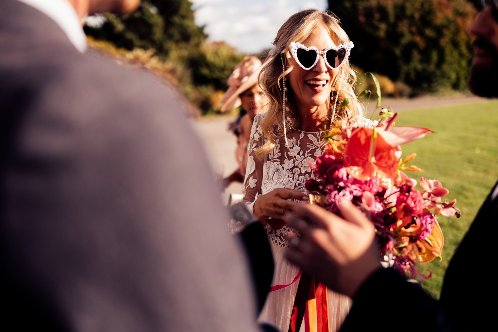 Bride with heart sunglasses carrying a lovely colourful bouquet