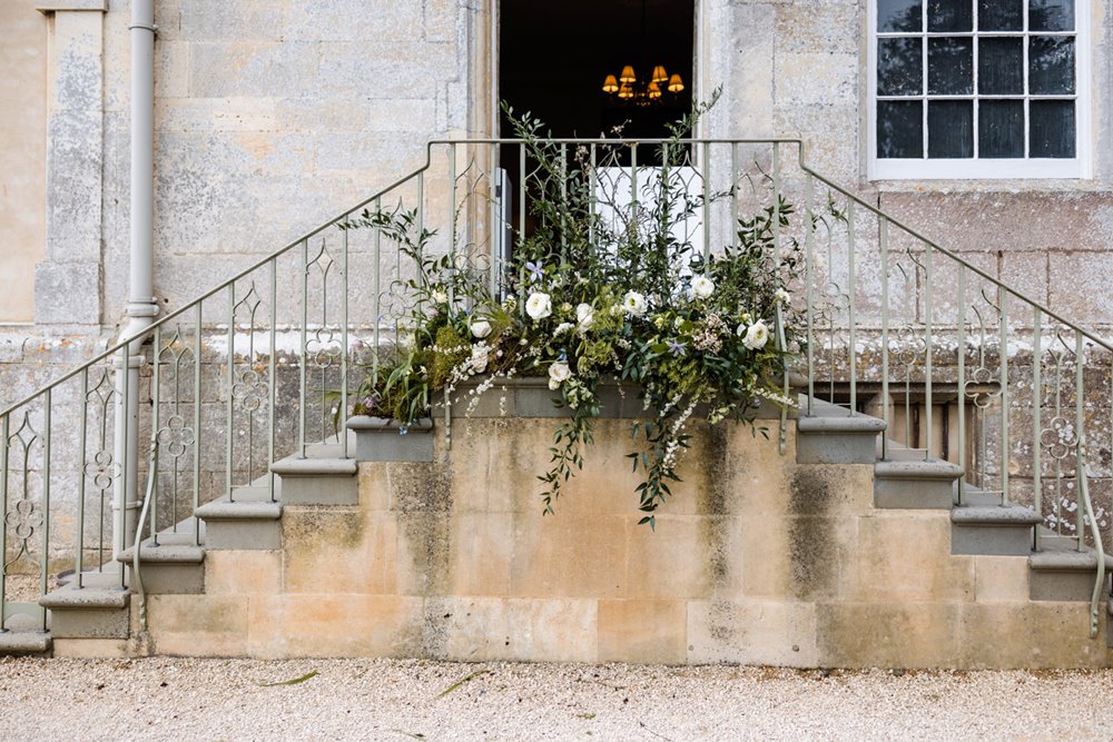 WIld wedding florals greenery decor on steps of elmore court for wedding fair in gloucestershire
