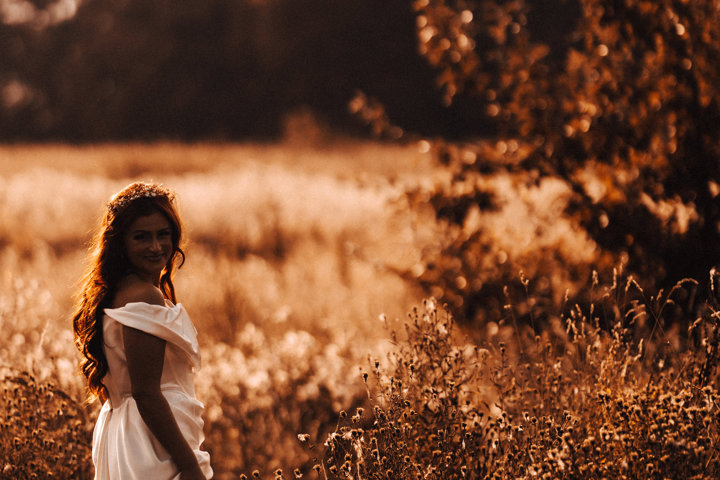 Glowing golden hour bride walking the fields in September sunshine