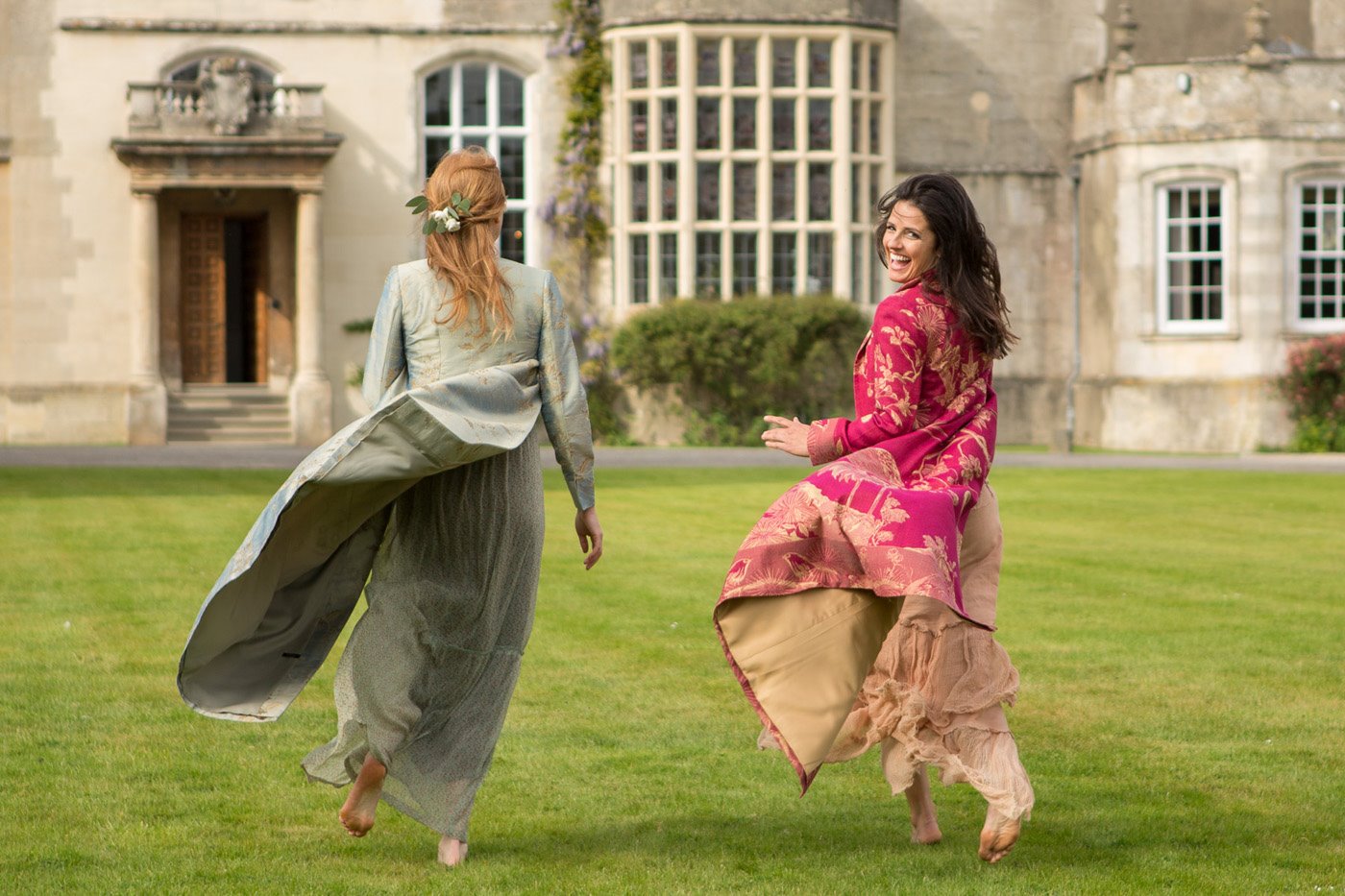 Women running towards wedding venue in beautiful flowing coats by Shibumi