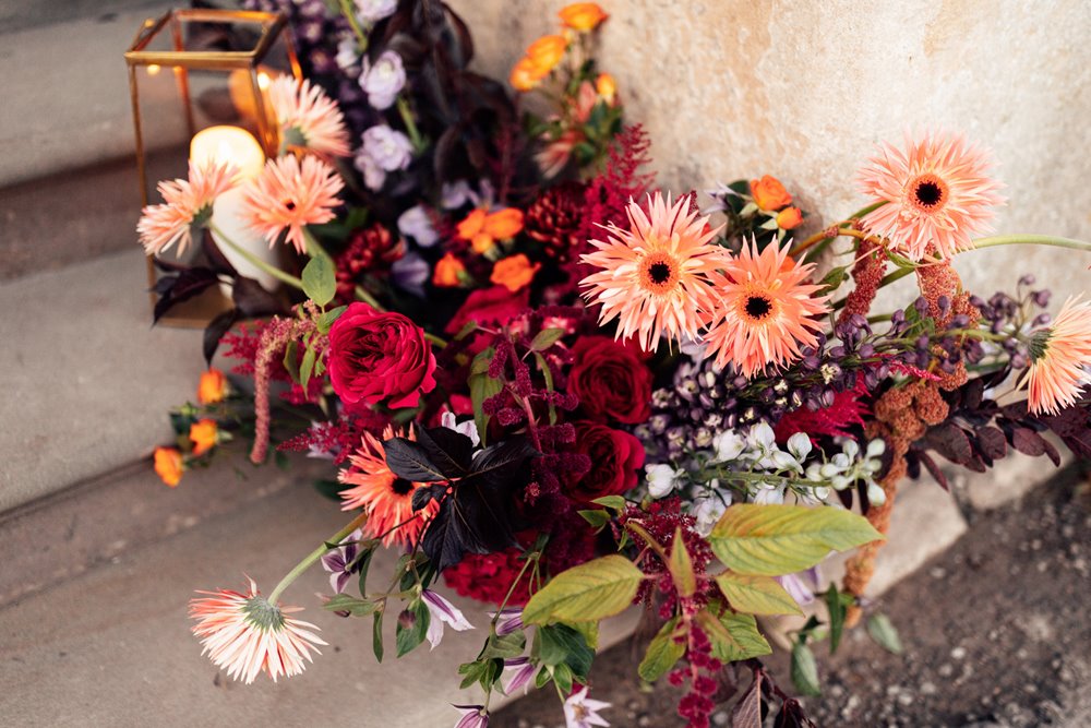 colourful wedding flowers and candles on the steps of mansion house wedding venue in gloucestershire