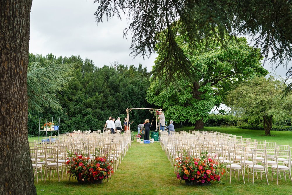 wedding flowers decorating the end of outdoor seating for jewish ceremony on the lawn