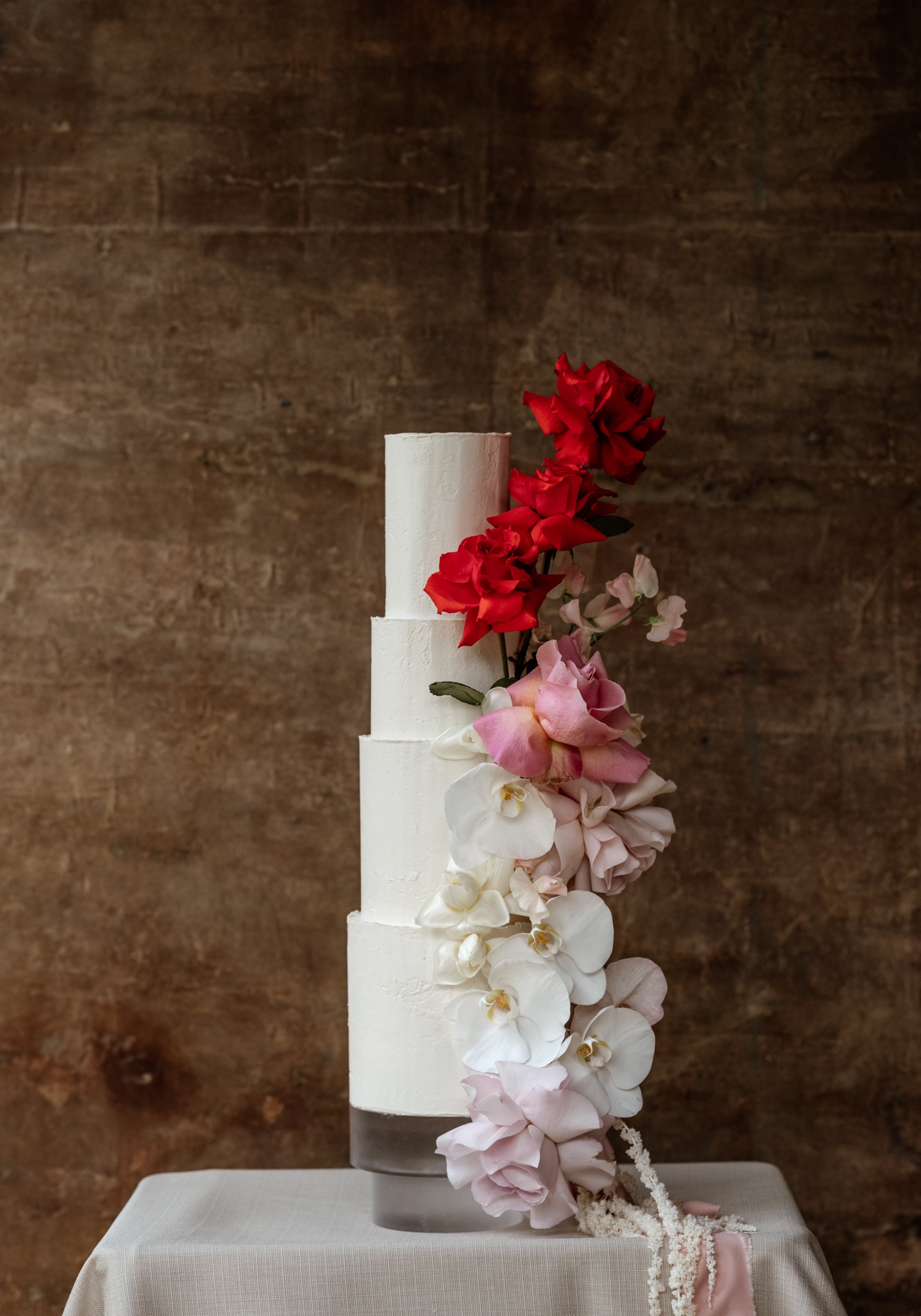 white wedding cake with red, pink and white flowers
