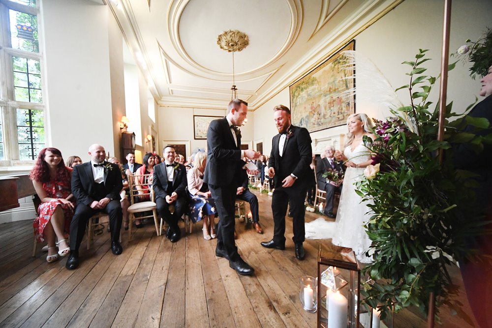 autumnal wedding ceremony with green foliage in beautiful stately home hall