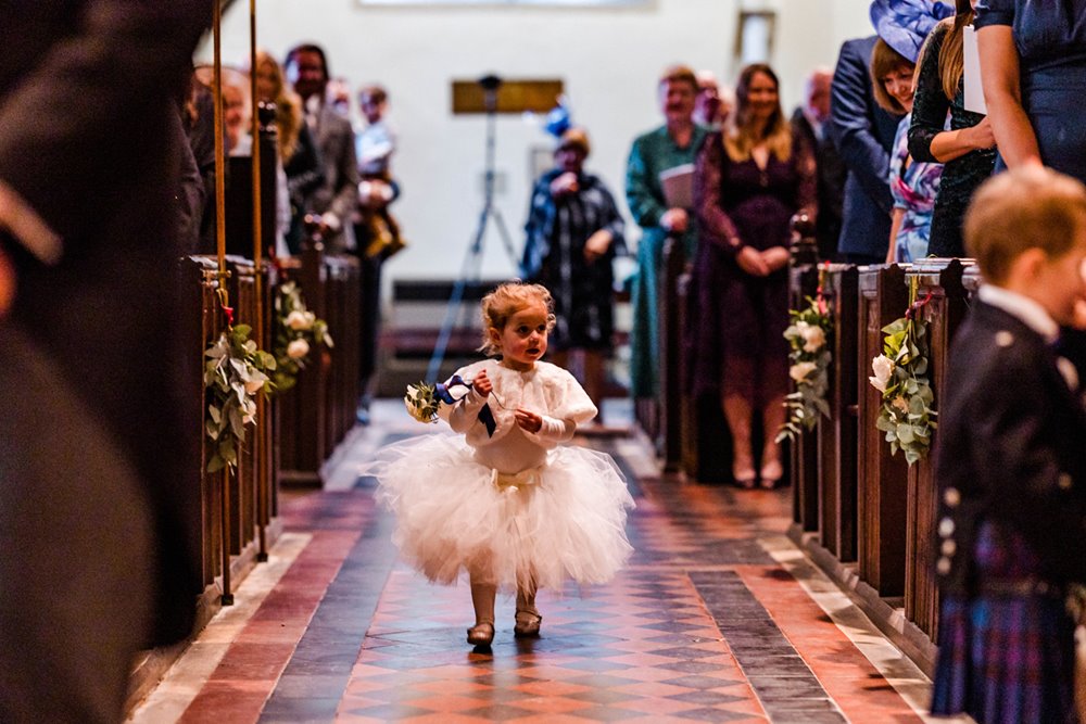 flower girl walking down aisle at church wedding in england