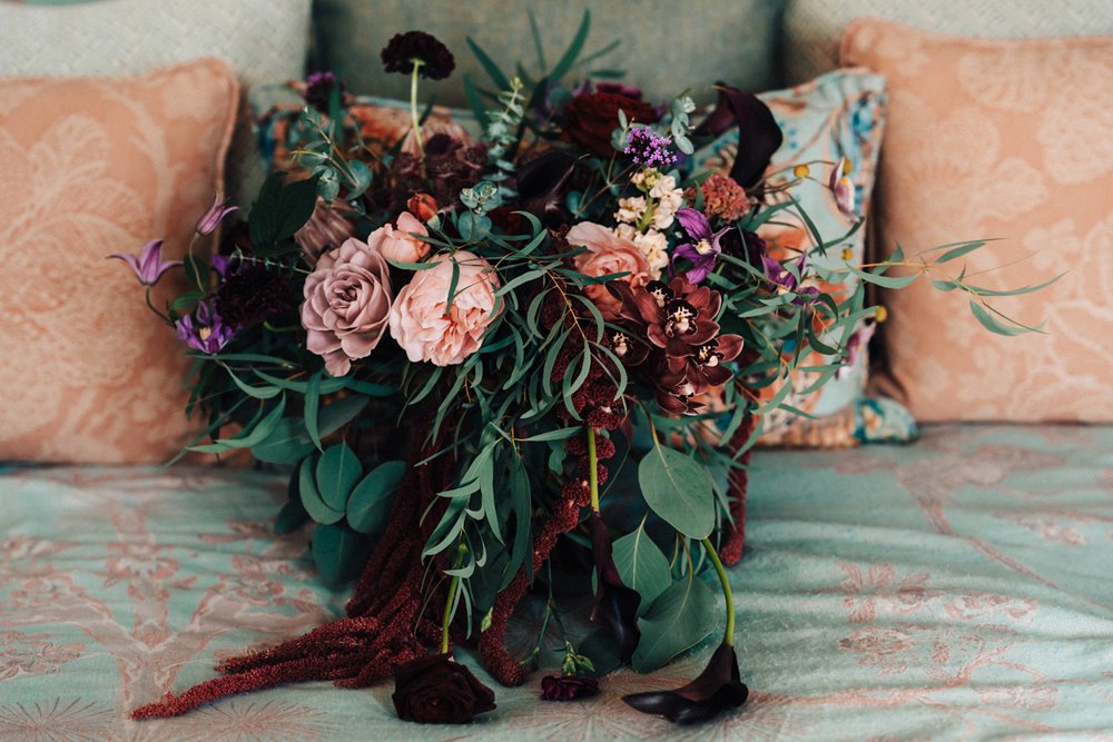 autumn wedding bouquet with dark flowers on a bed in stately home wedding venue elmore court