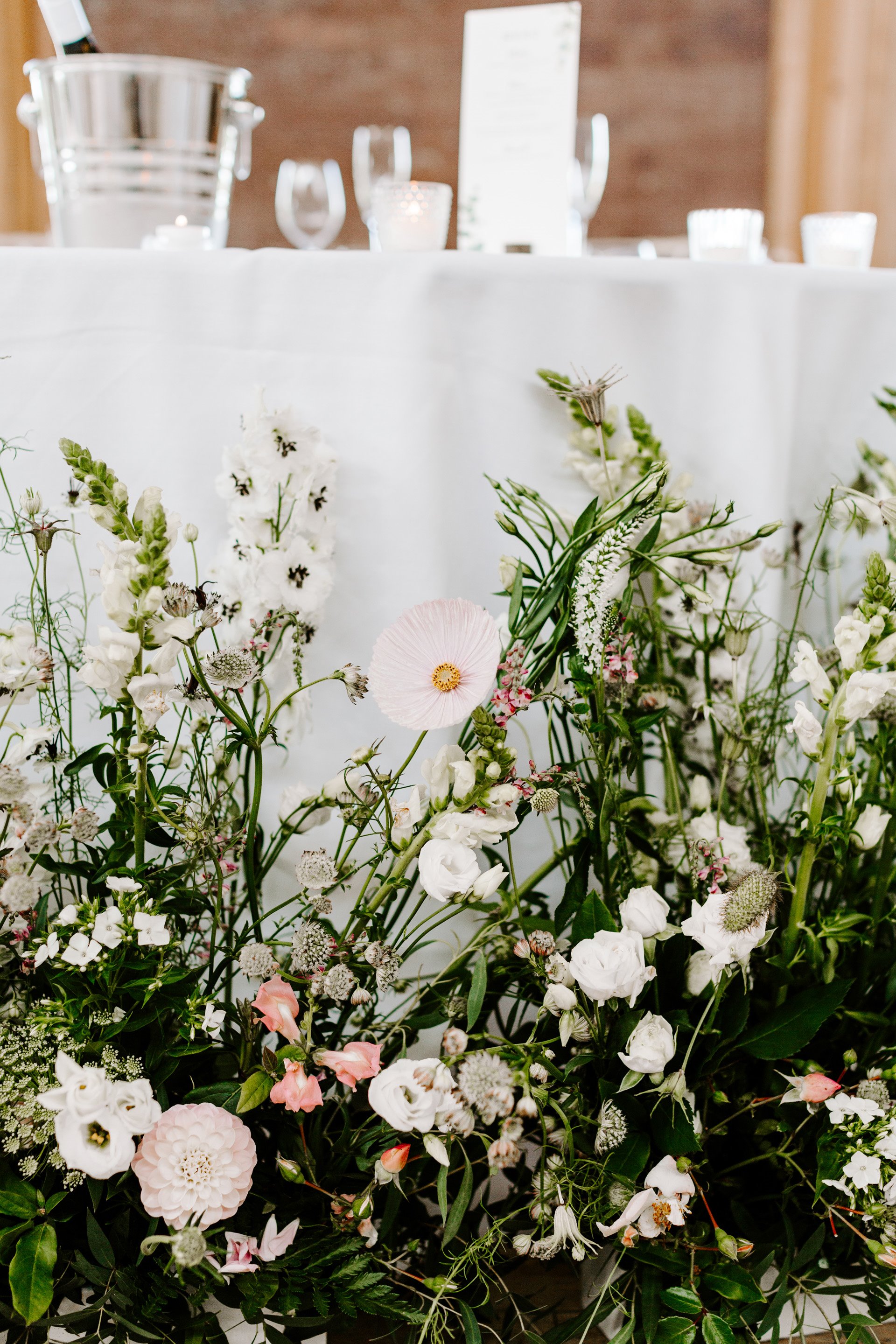 unique wild wedding flowers styling around the bottom of top table for a romantic wedding reception in the cotswolds