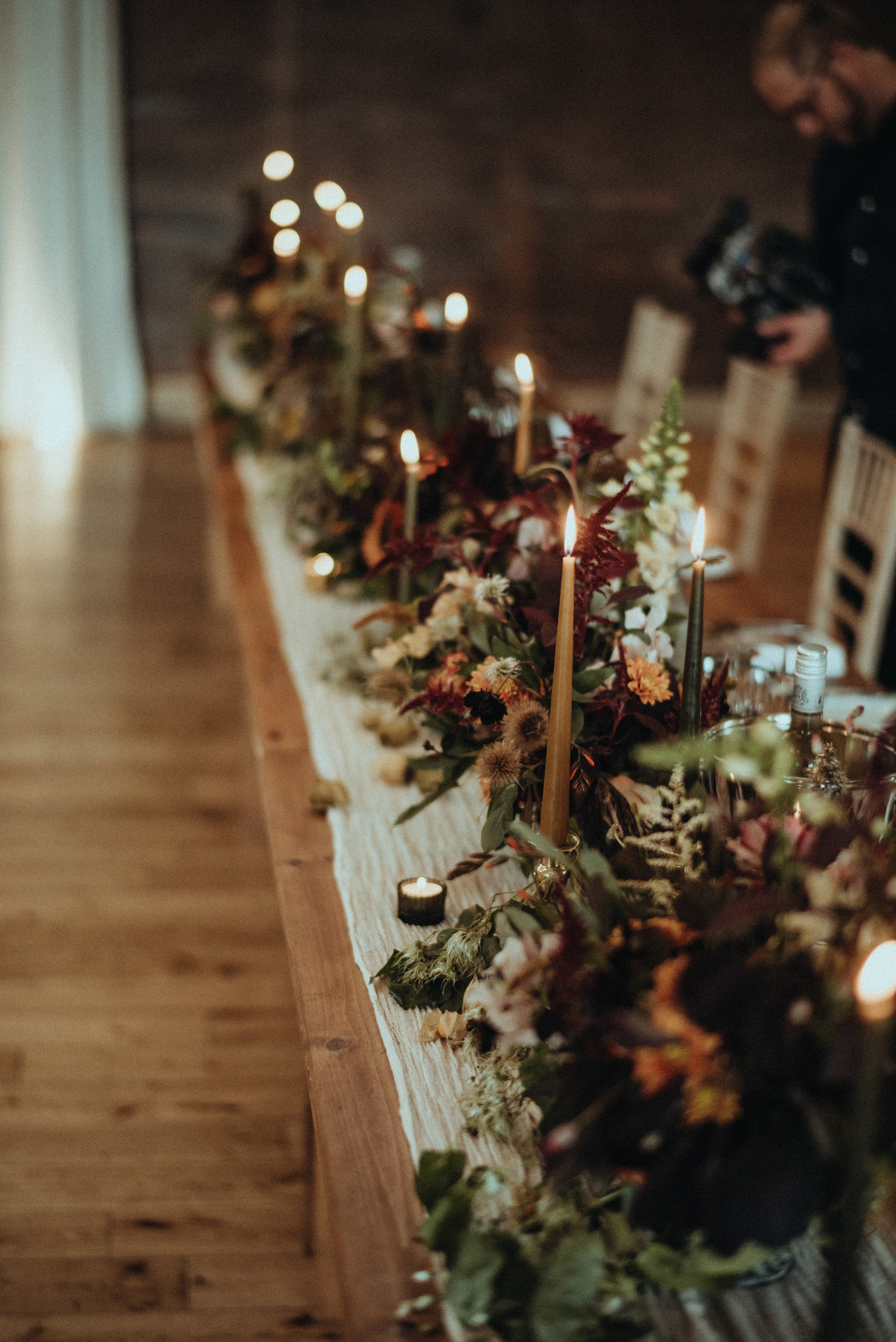 Candles and rustic decor on a long banqueting table for romantic wedding reception in the cotswolds