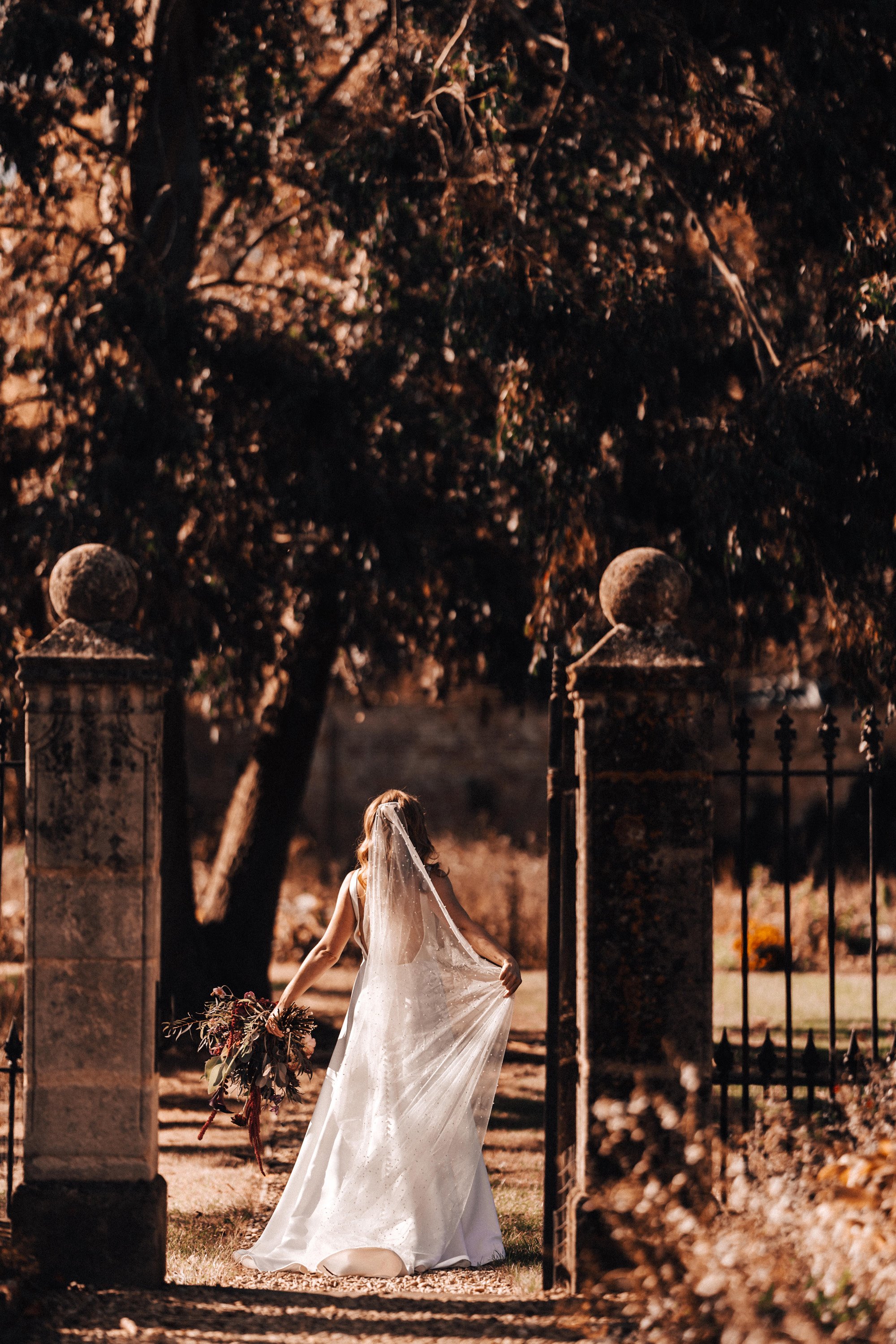 moody photo of bride in long veil in the walled garden at wedding venue elmore court in the autumn