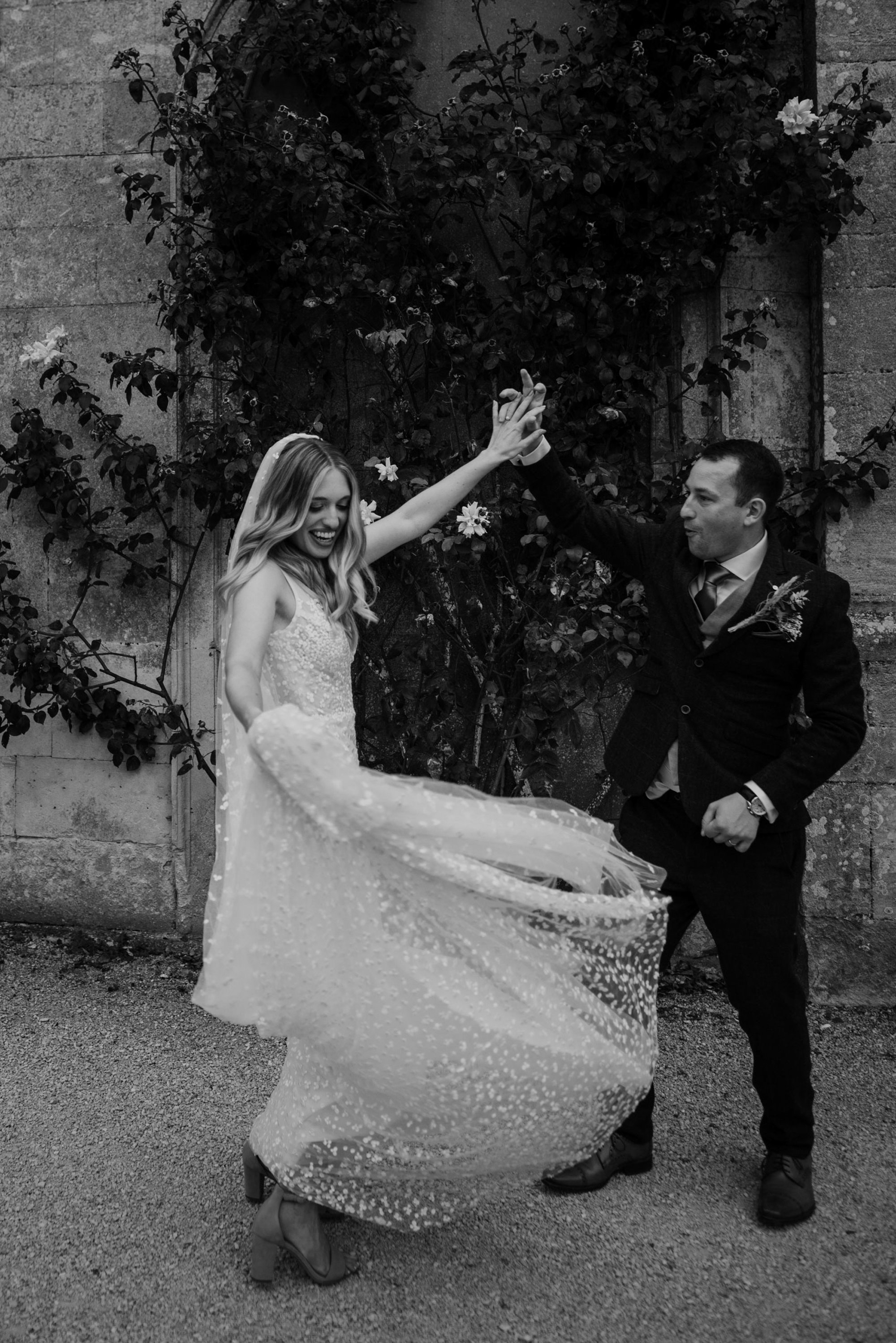 black and shite shot of a Groom twirling his new wife outside a stately home in Gloucestershire