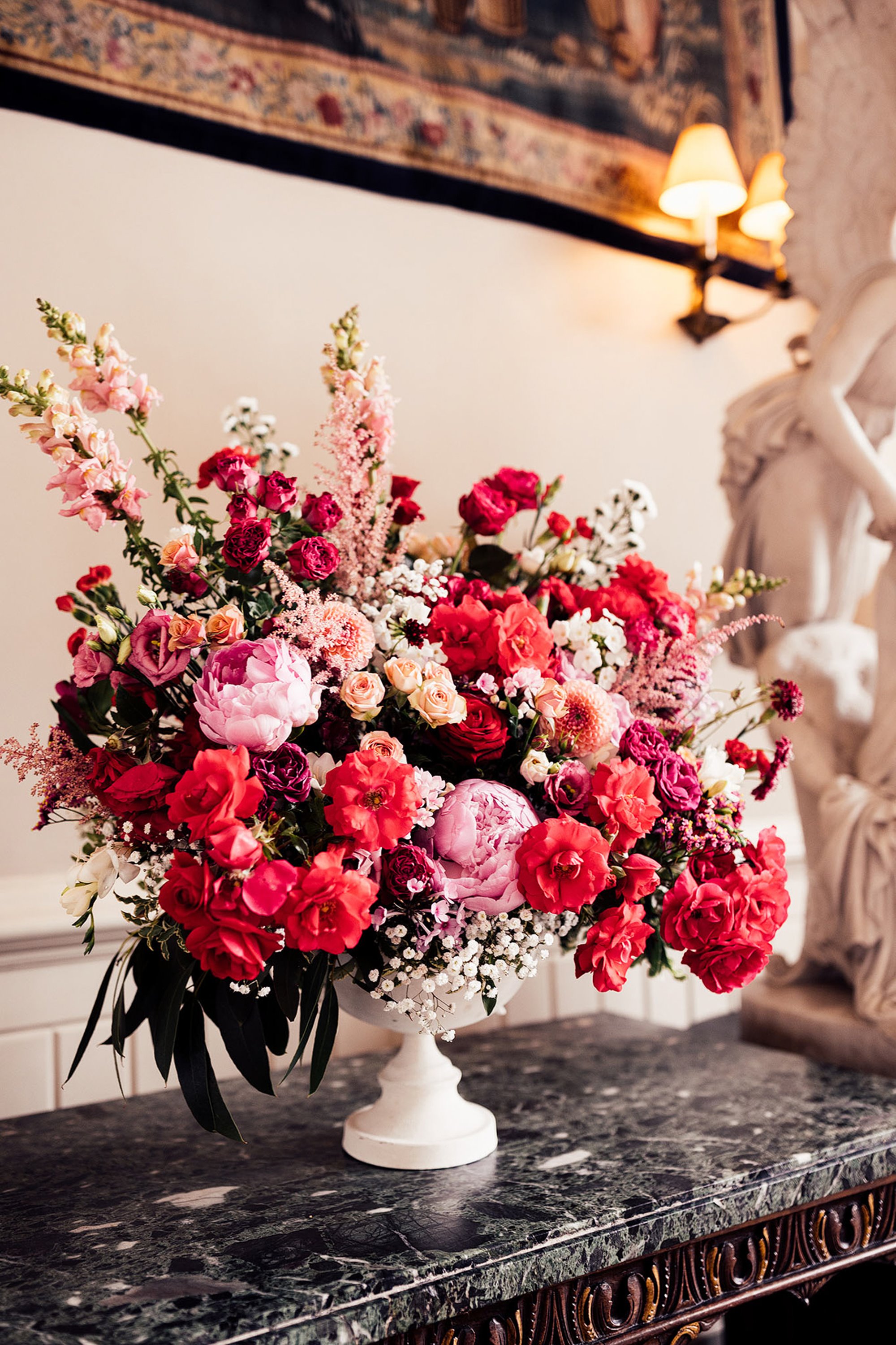 bouquet of pink and red flowers in a lovely white urn